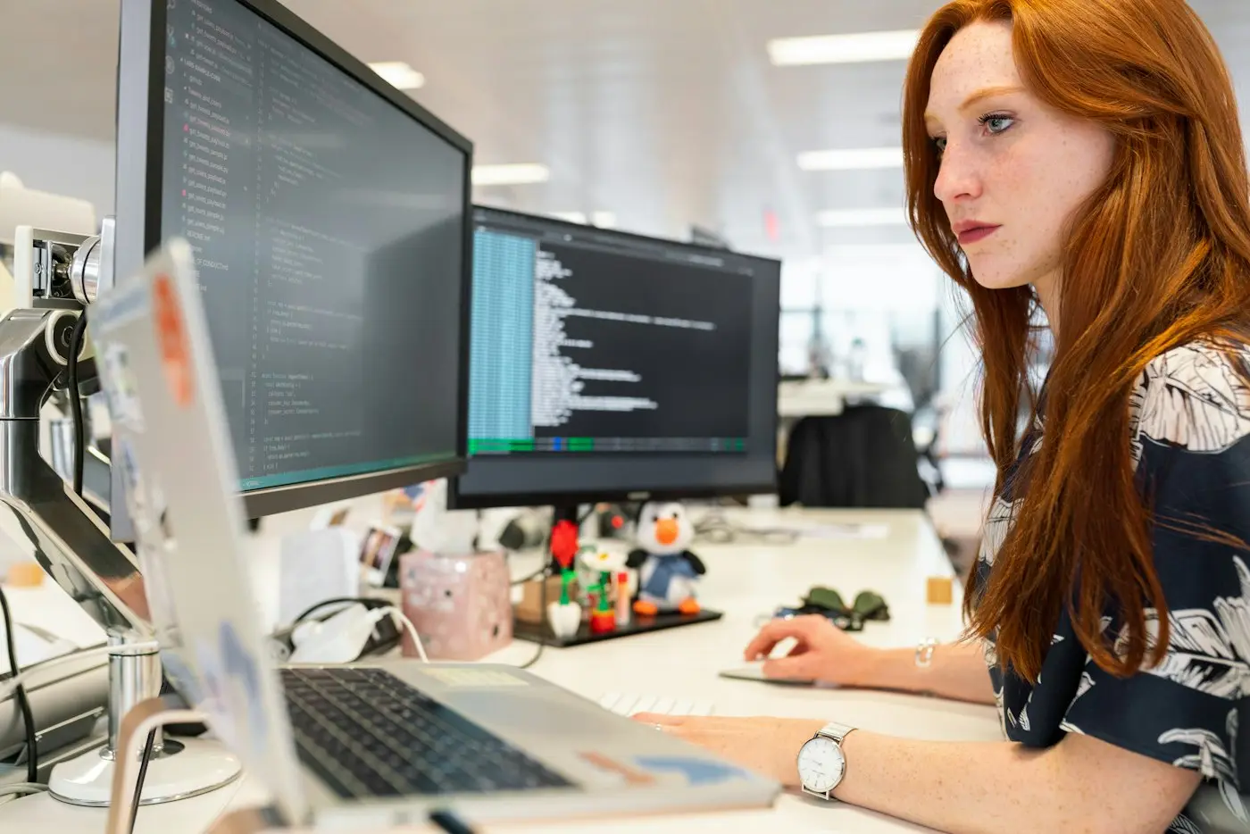 An engineer reading code across two monitors.