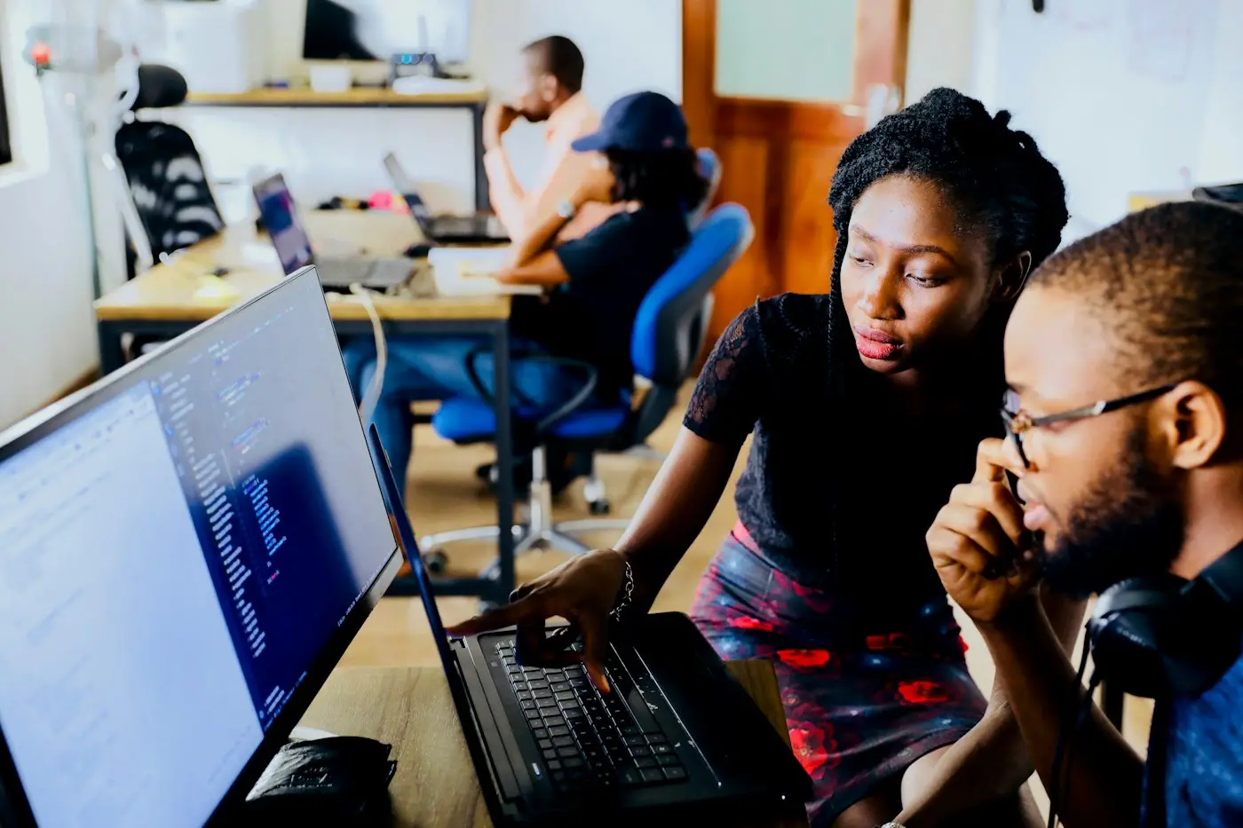 Two engineers working through a problem together at a laptop.