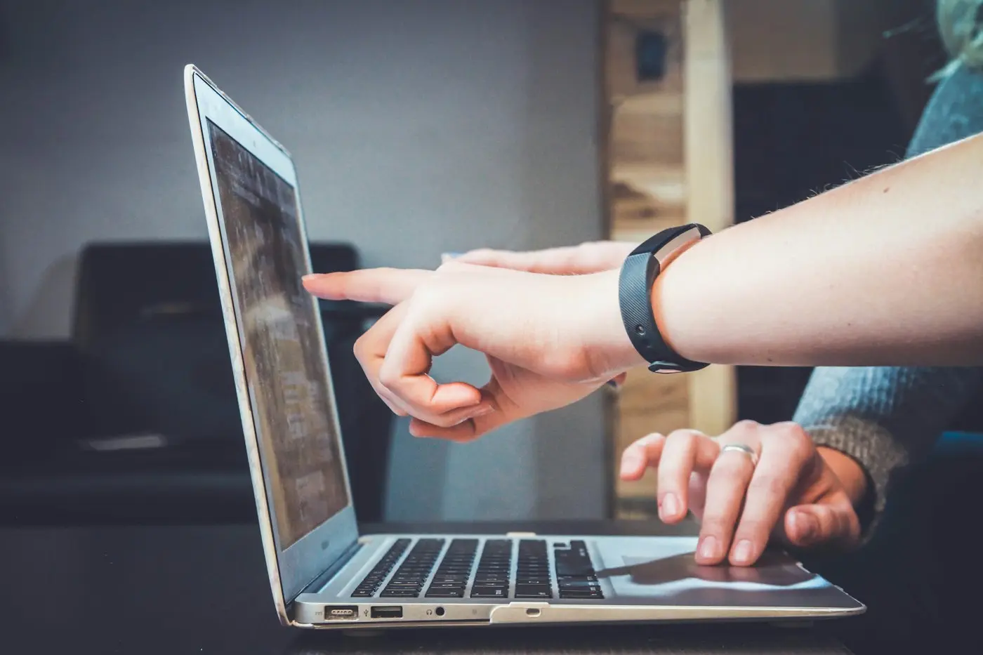 Two people reviewing work on a laptop, one pointing at the screen.
