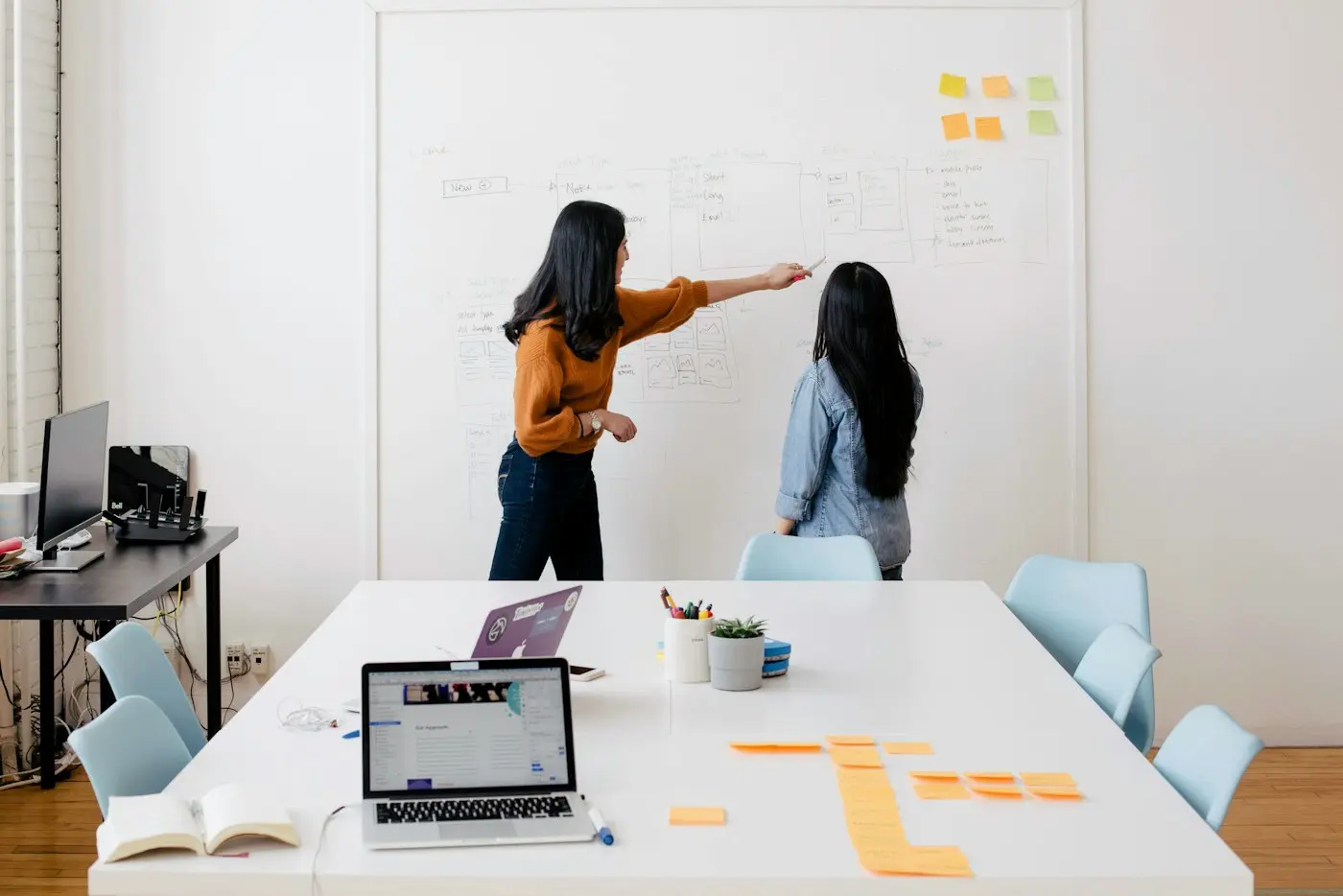 Two people working through a plan on a whiteboard.